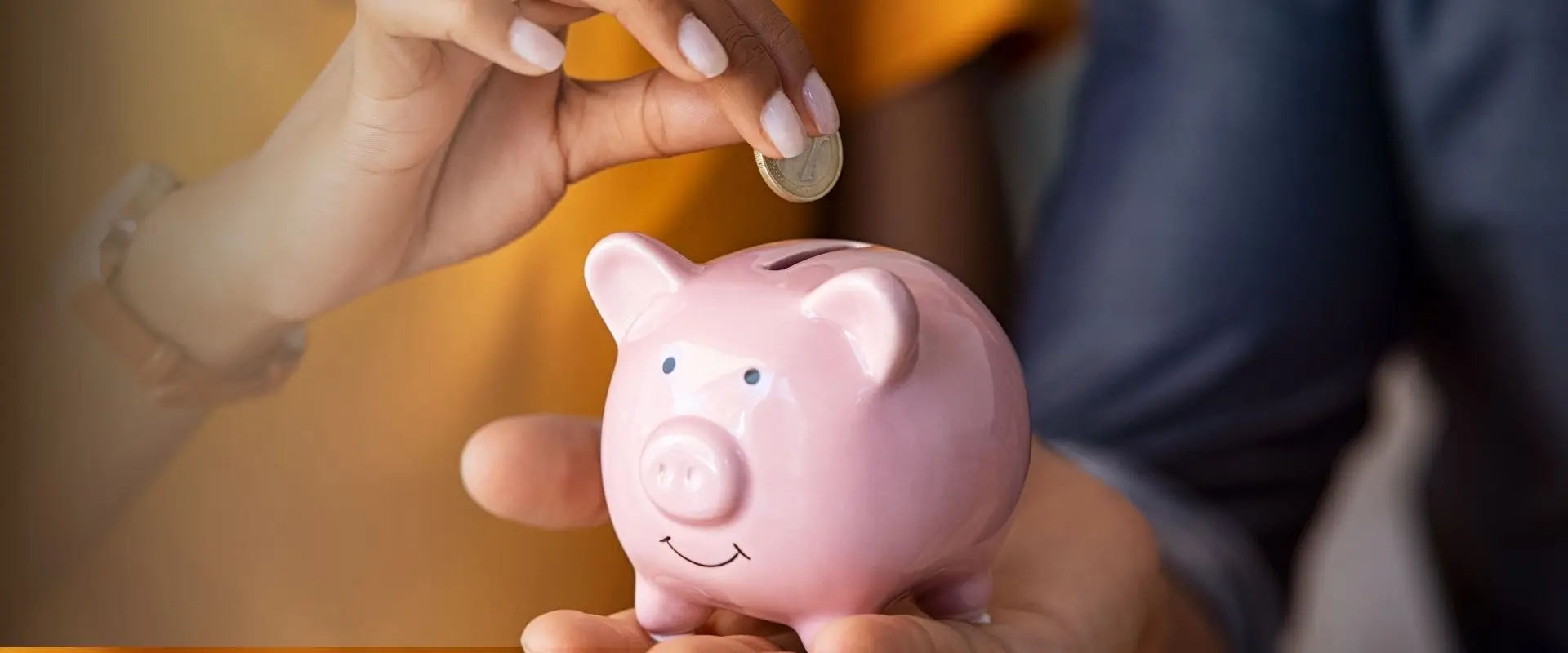 Mano depositando una moneda en una alcancía rosa; Vida Protección Bolívar protege tu crédito